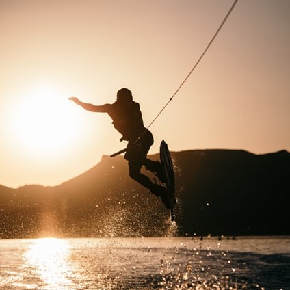 Man wake-boarding with the sun beam behind him